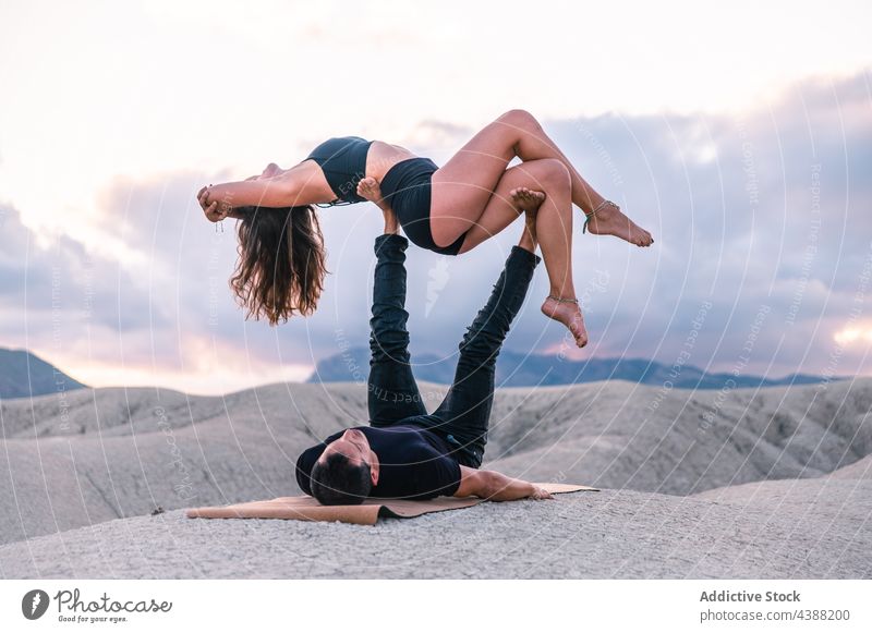 Flexibles Paar übt Acro-Yoga bei Sonnenuntergang Akro-Yoga akrobatisch Gleichgewicht abstützen Partner Zusammensein Berge u. Gebirge Himmel Partnerschaft Abend
