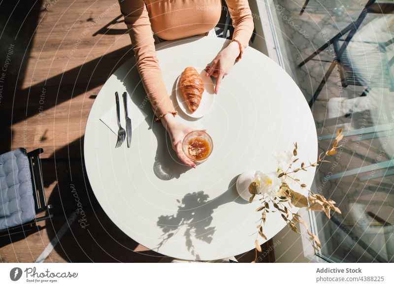 Anonyme Frau mit Kaffee und Croissant am Tisch in einem Cafe Café Dessert lecker geschmackvoll trinken Getränk Französisch aromatisch frisch genießen