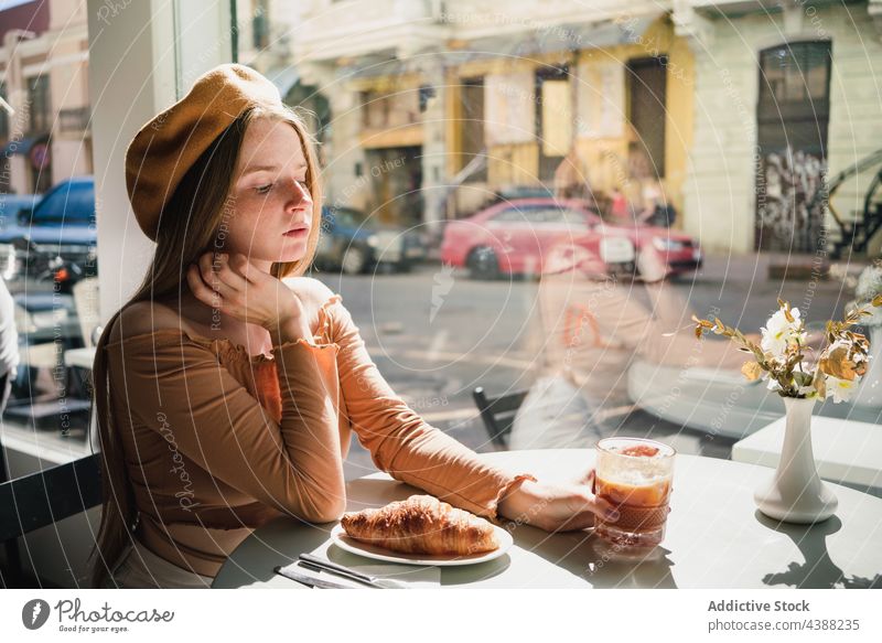 Frau mit Kaffee und Croissant am Tisch in einem Cafe Café Dessert lecker geschmackvoll trinken Getränk Französisch aromatisch frisch genießen Baskenmütze Gebäck