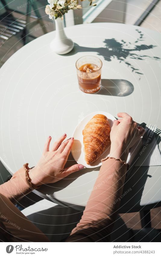 Anonyme Frau mit Kaffee und Croissant am Tisch in einem Cafe Café Dessert lecker geschmackvoll trinken Getränk Französisch aromatisch frisch genießen