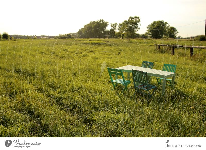 verlassener Tisch und Stühle auf einer Wiese mit Gras leer einsam sonnig Sommer Pause Tag Sitzgelegenheit Holzstühle Tourismus Coronavirus zugeklappt niemand