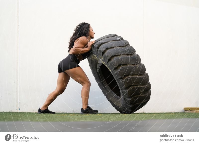 Starke ethnische Sportlerin, die beim Training einen Reifen umdreht Flip schwer stark muskulös Athlet Übung Fokus Frau konzentriert asiatisch Ausdauer passen