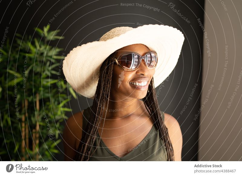 Fröhliche stilvolle schwarze Frau mit Sonnenhut und Sonnenbrille Stil trendy Sommer Outfit Strohhut heiter Glück ethnisch Afroamerikaner Hut positiv