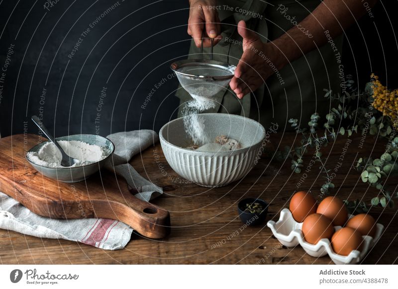 Anonymer Mann beim Backen von Gebäck sieben Mehl Küche Sieb Schalen & Schüsseln Lebensmittel Bestandteil Prozess Pulver Utensil Tisch vorbereiten organisch