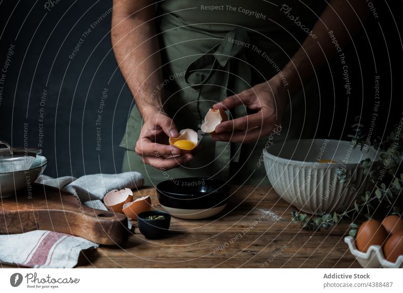 Kappenmann schlägt Ei für Gebäck auf Mann Pause Koch Schalen & Schüsseln Tisch Küchengeräte roh rustikal männlich Küchenchef Holz hinzufügen frisch vorbereiten