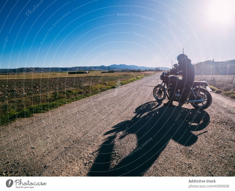 Unbekannter Motorradfahrer fährt auf einer Landstraße Mitfahrgelegenheit Fahrrad Straße Landschaft Person Laufwerk ländlich Fahrzeug Verkehr reisen Abenteuer