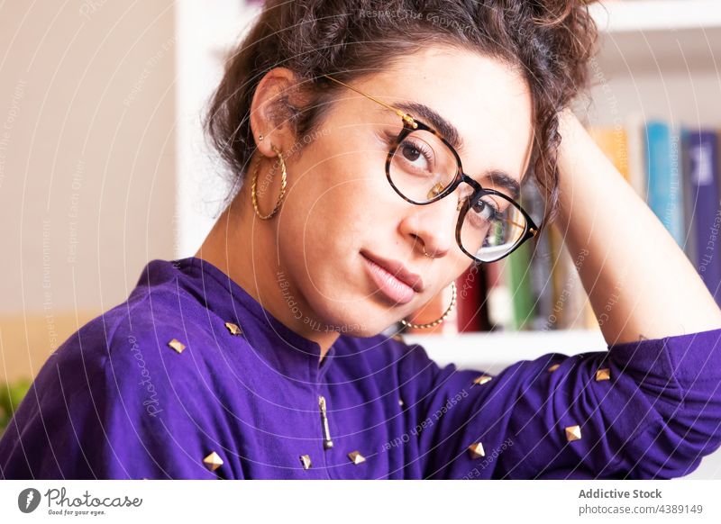 Ethnische Frau mit Brille schaut in die Kamera Stil Porträt zu Hause jung trendy Menschliches Gesicht starren ethnisch hispanisch brünett nachdenklich