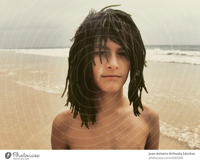 Nahaufnahme eines Jungen am Strand, der eine Perücke aus Seegras trägt 12 Jahre Porträt bizarr MEER Sommer Kind Youngster jung Mann Kaukasier Freizeit