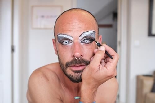 Bärtiger Mann trägt Make-up auf die Augen auf bewerben Drag Queen Transgender Kajal Augenbraue Kosmetik Geschlecht Gesicht Linse männlich Piercing Vollbart