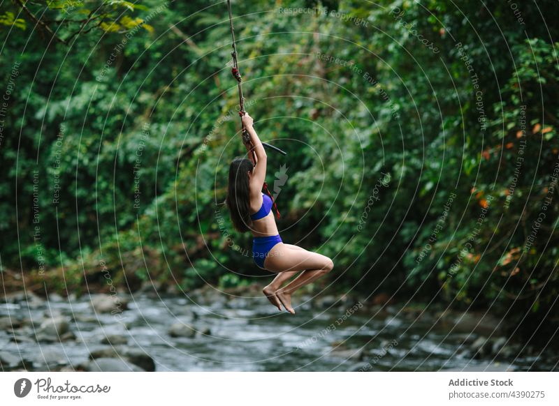 Frau am Seil, die über einen Fluss springt Bungee springen Wald Abenteuer Aktivität reisen strömen jung aktiv extrem Natur Urlaub Sommer Feiertag Tourismus