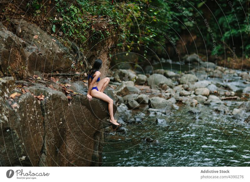 Frau sitzt in der Nähe eines Flusses im Wald Felsen Natur Reisender Wasser Stein sich[Akk] entspannen allein ruhen Tourist Urlaub reisen Erholung Costa Rica