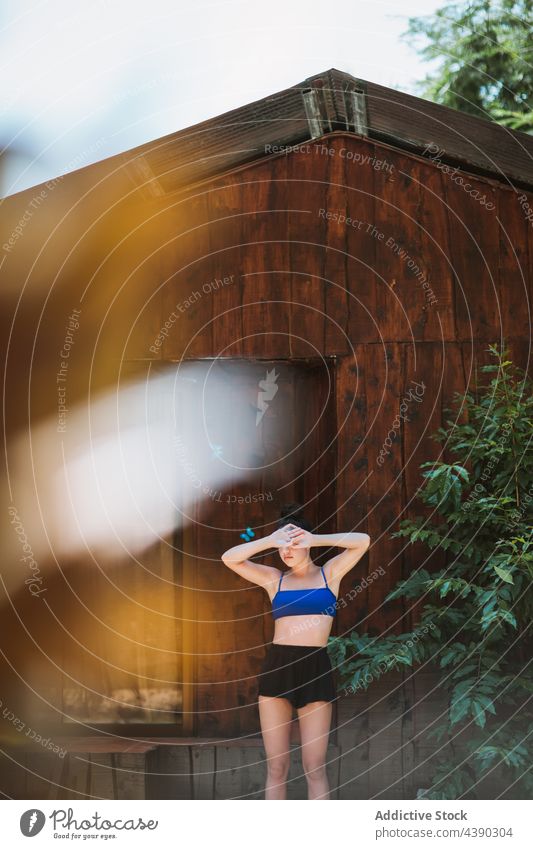 Anonyme Frau, die an einer Holzwand mit Schmetterlingen steht Natur Haus hölzern Wand Sommer tropisch reisen blau jung Urlaub Badebekleidung Farbe Feiertag