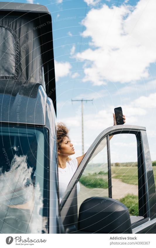 Frau mit Smartphone in kaputtem Auto PKW Wohnmobil Ärger Problematik gebrochen Anschluss Fahrer Reisender jung Afroamerikaner schwarz ethnisch Mobile Telefon