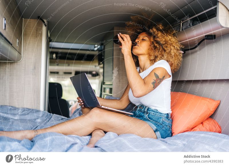 Ethnische Frau chillt im Wohnmobil Kleintransporter Laptop benutzend ruhen Bier Sommer Reisender Feiertag Afroamerikaner schwarz ethnisch trinken jung Urlaub