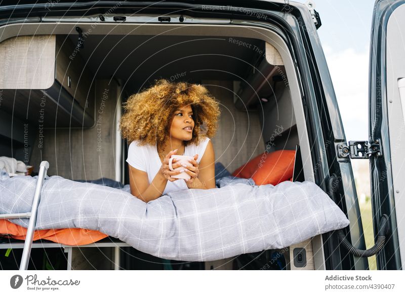 Schwarze Frau trinkt Heißgetränk im Wohnwagen Autoreise Bett Harmonie genießen Morgen Sommer ruhen Wochenende jung Kaffee sich[Akk] entspannen ethnisch