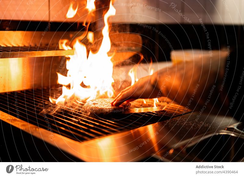 Kropfenkoch grillt Patty auf dem Grill in der Küche Küchenchef Grillrost Burger Pastetchen Flamme Feuer Koch Mann vorbereiten Restaurant männlich Lebensmittel