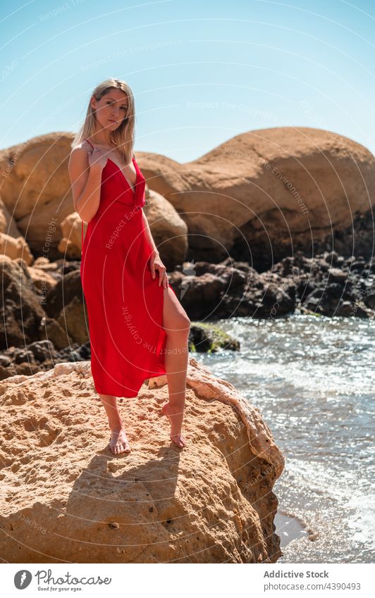 Frau in rotem Kleid am Meeresstrand Strand felsig Stil Sommer Mode MEER Farbe jung blond Barfuß Outfit Aussehen Sonnenkleid Ufer Küste Natur Meeresufer Seeküste