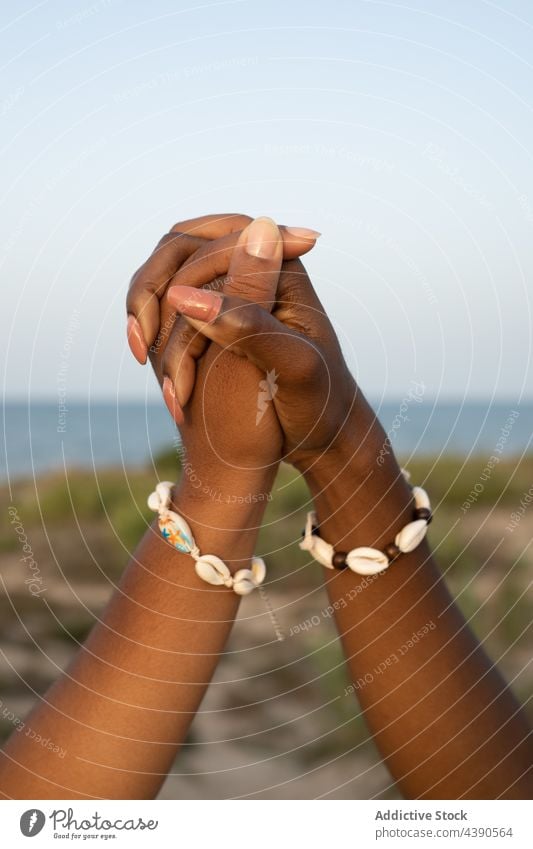Schwarze Freundinnen halten sich am Meeresufer an den Händen Frauen Freundschaft Händchenhalten Sommer Armband Panzer Zusammensein bester Freund Partnerschaft