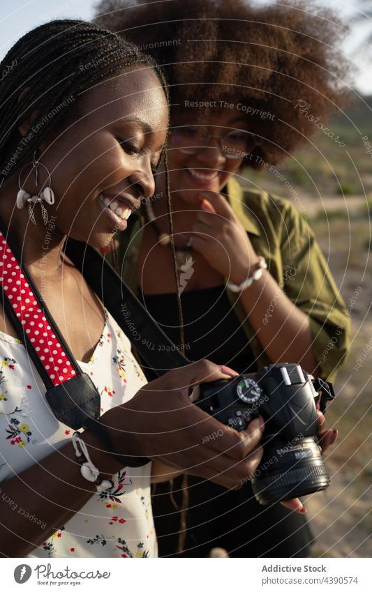 Glückliche schwarze Freundinnen mit Fotoapparat im Sommer in der Natur Zusammensein Stil heiter Urlaub Feiertag jung Frauen Afroamerikaner ethnisch