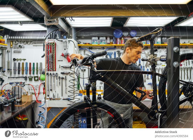 Mann repariert Fahrradrad in der Garage Techniker Reparatur befestigen Rad professionell Arbeit Dienst männlich Erwachsener Fahrradfahren Mechaniker Werkstatt