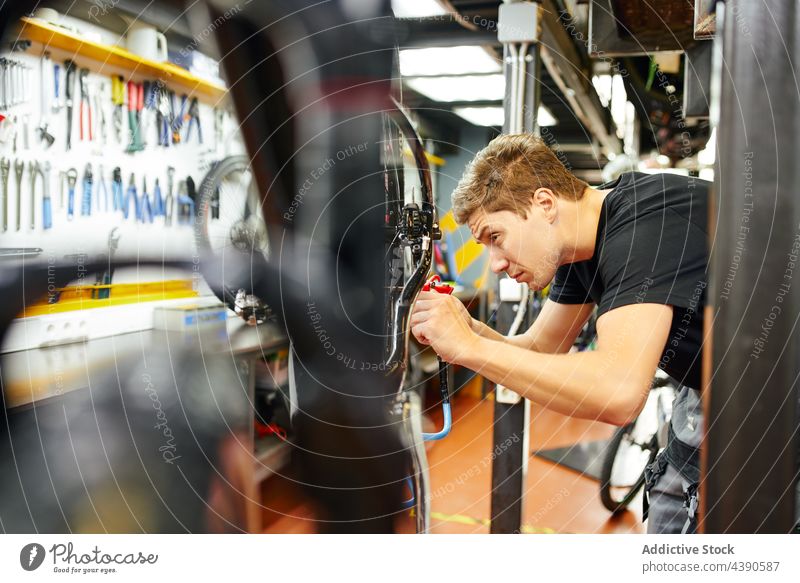 Konzentrierter Mechaniker beim Aufpumpen eines Fahrradreifens in einer Garage Werkstatt Pumpe Reifen Pistole Mann Rad aufblasen Dienst männlich Werkzeug Arbeit