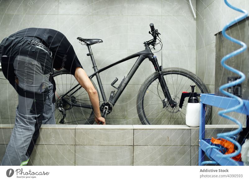 Anonymer Mann beim Reinigen der Schaltkassette eines Fahrrads Waschen Rad Ausrüstung Kassette Sauberkeit Bürste Werkstatt Wasser männlich schäumen übersichtlich