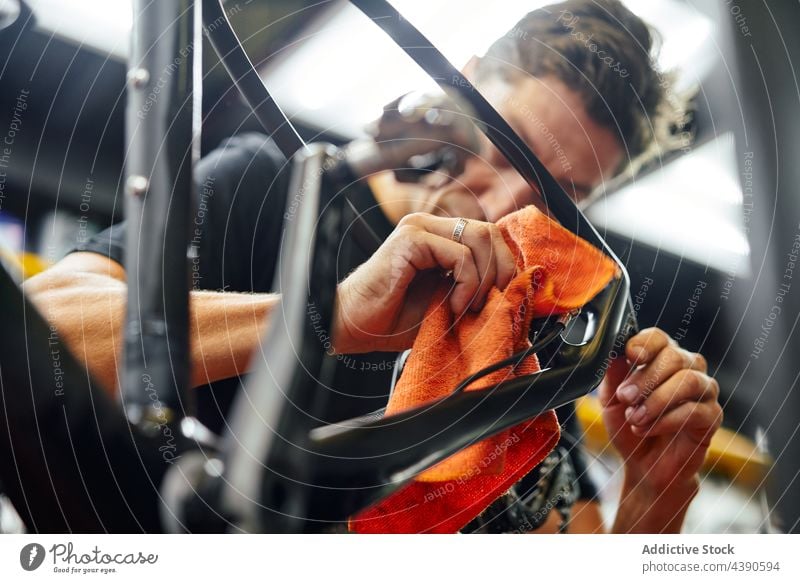 Männlicher Mechaniker beim Abwischen des Fahrradrahmens in der Werkstatt Mann Rahmen Wischen Sauberkeit Dienst übersichtlich männlich Tuch Arbeit Gerät