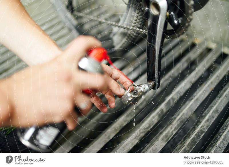 Crop Mann reinigt Fahrradpedal in der Werkstatt Sauberkeit Pedal übersichtlich Spray Dienst Reparatur männlich Gerät Arbeit professionell Job Mechaniker Metall