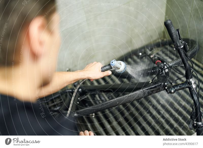 Unbekannter Mann wäscht Fahrrad in Werkstatt Waschen Wasser Sauberkeit übersichtlich Dienst Arbeit männlich Gerät professionell Job Mechaniker Reparatur Metall