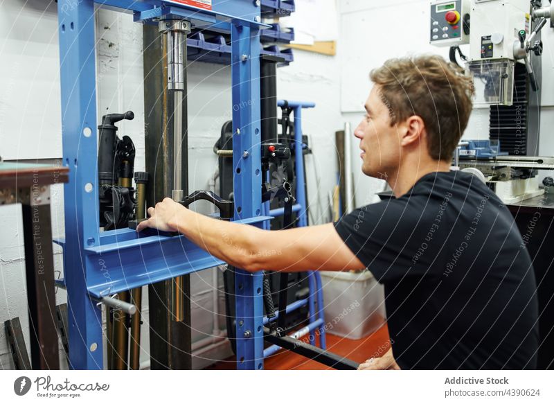 Männlicher Mechaniker mit hydraulischer Presse Mann Werkstatt Arbeit Reparatur professionell Beruf Industrie männlich Kleinunternehmen Erwachsener Gerät