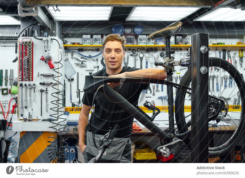 Gut gelaunter Mann in einer Fahrradwerkstatt Mechaniker Werkstatt Reparatur professionell Lächeln fettarm Arbeit Industrie männlich Erwachsener Kleinunternehmen
