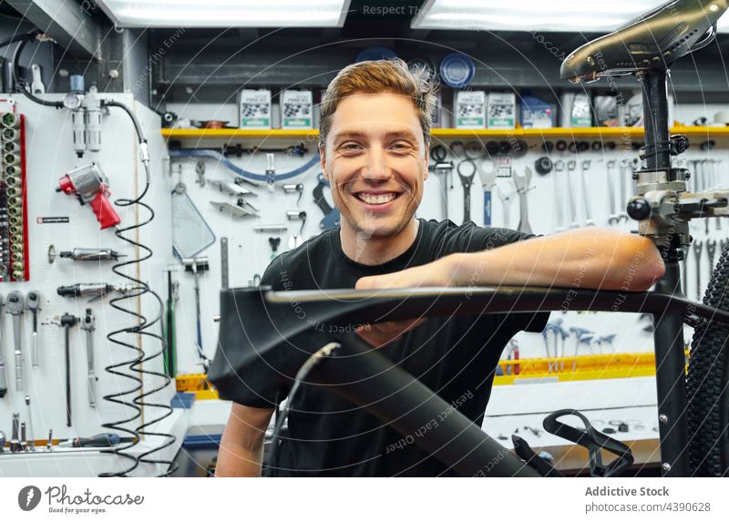 Gut gelaunter Mann in einer Fahrradwerkstatt Mechaniker Werkstatt Reparatur professionell Lächeln fettarm Arbeit Industrie männlich Erwachsener Kleinunternehmen