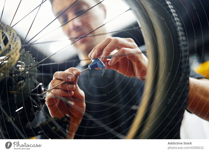 Mechaniker schraubt Fahrradrad ein Mann Rad fixieren schrauben Arbeit Garage manuell Dienst männlich Schraubendreher Reparatur Werkstatt Fahrzeug Verkehr