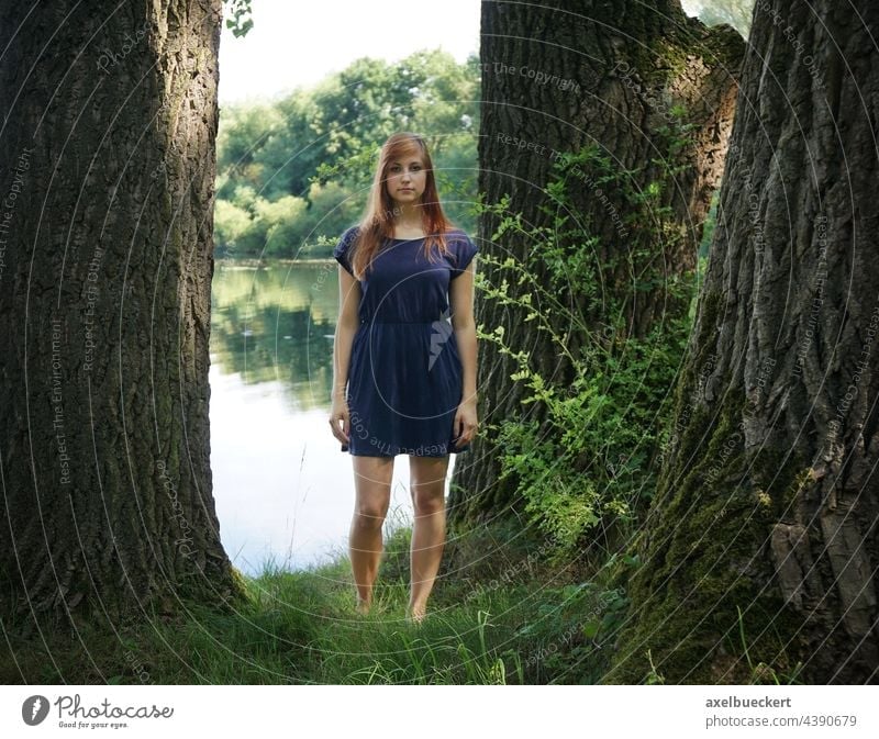junge Frau steht im Sommerkleid zwischen Bäumen am See Junge Frau Badesee Wasser Schwimmen & Baden Ferien & Urlaub & Reisen Jugendliche Erholung Natur