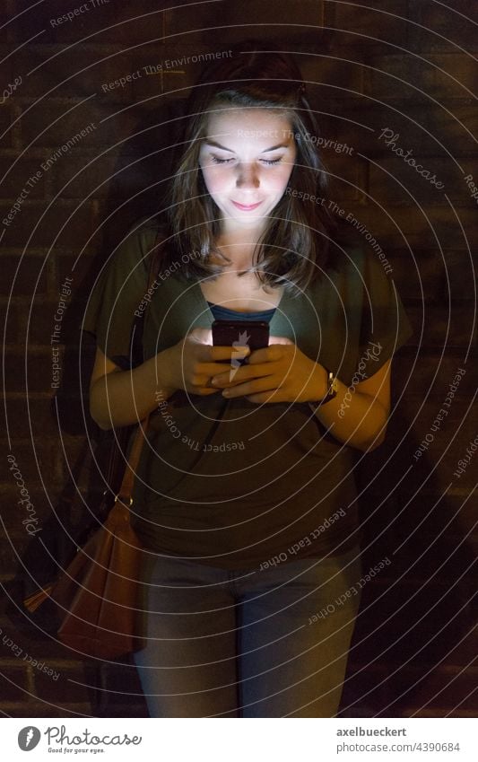 junge Frau benutzt Handy im Dunkeln benutzend Smartphone Licht Lichtschein Beleuchtung leuchten Technik & Technologie Lifestyle Telefon Internet Texten
