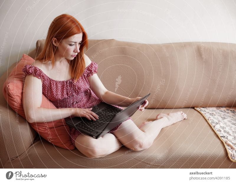 Frau, die zu Hause einen Laptop benutzt und sich auf dem Sofa entspannt zuhause benutzend Computer authentisch Wohnzimmer Arbeit Heimarbeitsplatz freiberuflich
