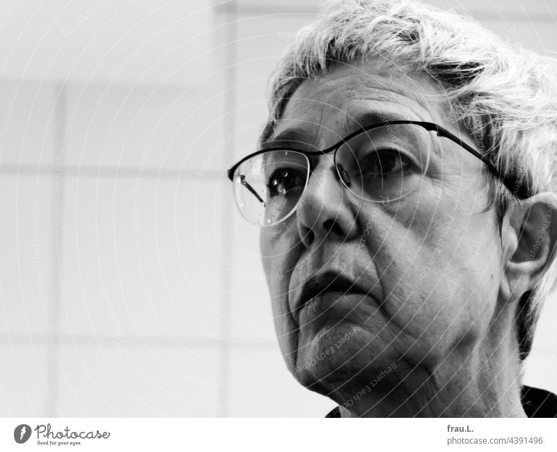 Alte Frau mit Wassertropfen auf der Brille Porträt Gesicht Kacheln Fliesen graue Haare erstaunt genervt Falten androgyn Gesichtsausdruck Kopf