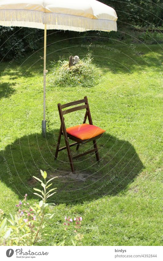 Einzelner Stuhl im Schatten eines Sonnenschirms auf einem Rasen Sonnenlicht Schattenplatz Garten Hitze Schönes Wetter Gras Klappstuhl Sitzplatz Sommer