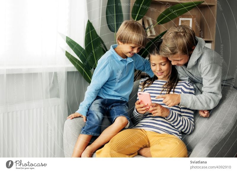 Kinder sitzen zu Hause auf der Couch, spielen Spiele am Telefon, chatten mit Freunden. Moderne Technologie und Zeit zu Hause verbringen heimwärts Tablette