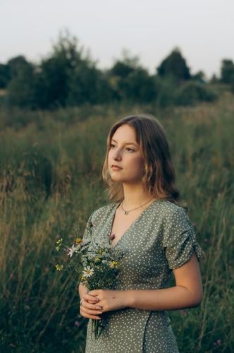 Ein junges Mädchen hält einen Strauß mit Wildblumen in den Händen. Blumenstrauß cottagecore-Ästhetik Frischluft Landschaft langsames Leben pastorales Leben