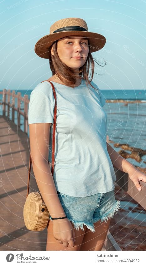 Teenager-Mädchen steht auf einer Holzbrücke am Meer Sonnenuntergang Jugendlicher blau Attrappe Kaukasier MEER Strohhut Bürgersteig im Freien Urlaub reisen