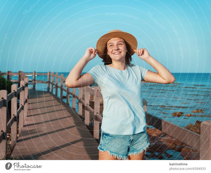 Teenager-Mädchen steht auf einer Holzbrücke am Meer Sonnenuntergang Jugendlicher blau Attrappe Kaukasier MEER Strohhut Bürgersteig im Freien berühren Urlaub