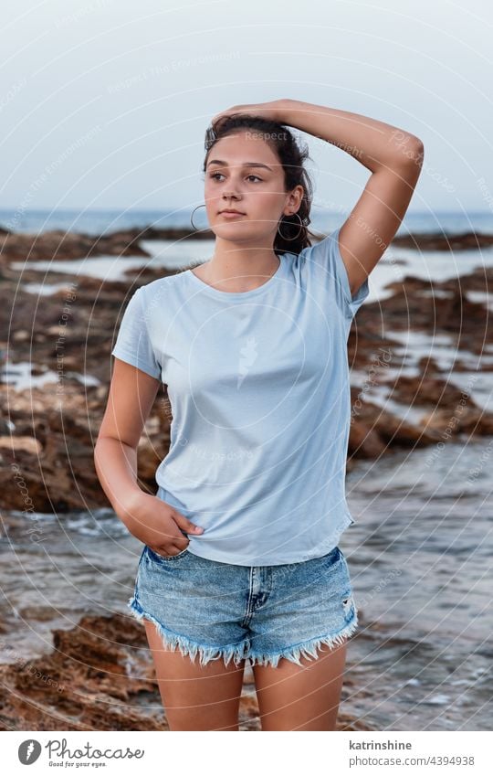 Teenager-Mädchen steht auf einer Klippe am Meer Attrappe blau Kaukasier MEER Felsen Sonnenuntergang Jugendlicher Stein tragend T-Shirts Stehen Kindheit Frau
