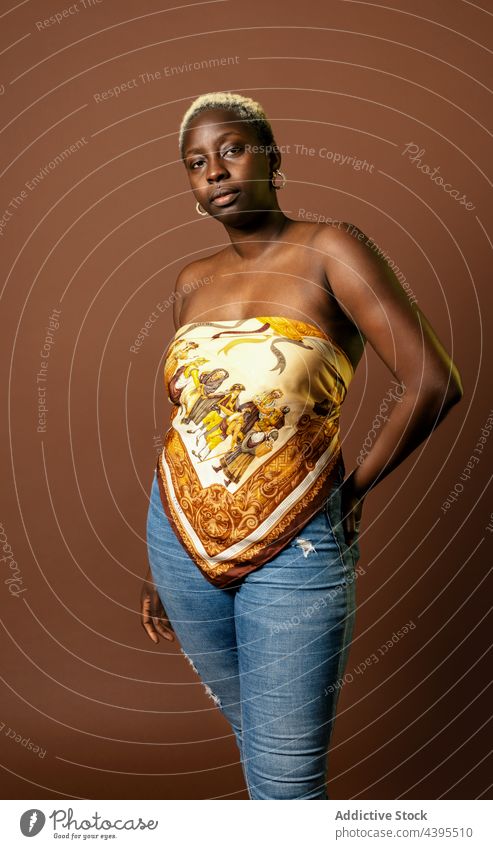 Stilvolle schwarze Frau auf braunem Hintergrund Model Seide Schal Top trendy Tasthals selbstbewusst ethnisch Afroamerikaner Outfit Bekleidung ernst blond