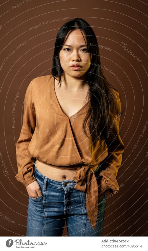 Asiatische Frau in stilvollem Outfit im Studio schaut in die Kamera Stil Atelier Bekleidung Model Freude trendy Vorschein asiatisch ethnisch Lächeln positiv