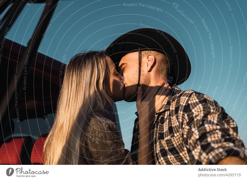 Verliebtes Paar küsst sich in der Nähe des Autos Kuss PKW Liebe Blauer Himmel romantisch Abend Sommer Partnerschaft Zusammensein Zuneigung Cowboy Angebot jung