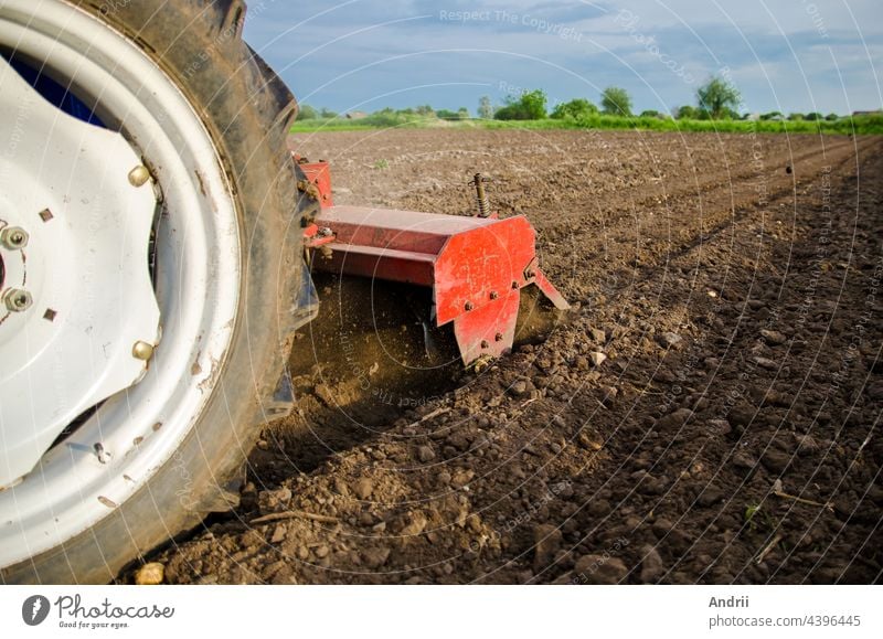 Ein Traktor mit Mähwerk kultiviert das Feld. Locker zerkleinerter, feuchter Boden nach der Kultivierung mit einem Grubber. Auflockerung der Oberfläche, Bodenbearbeitung. Ackerbau. Einsatz von Landmaschinen