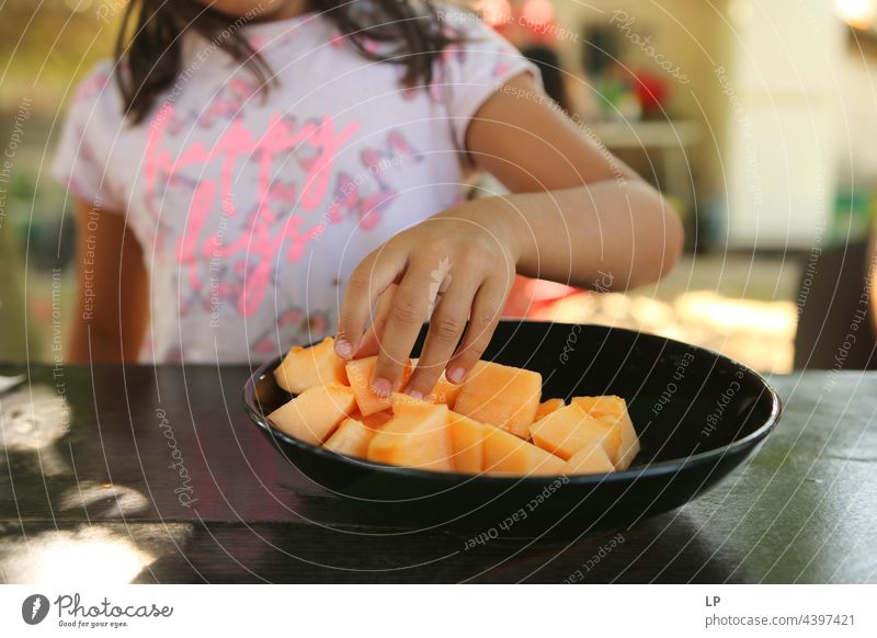 Hand eines Kindes, das ein Stück Melone von einem schwarzen Teller nimmt Familie & Verwandtschaft Kindheit Bildung Kindererziehung Freizeit & Hobby Sinnesorgane
