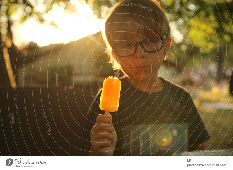 Junge isst ein Eis und sieht aus, als würde er über etwas nachdenken Blick Vernehmung aussruhen entdeckend erkennen Fleck wahrnehmen Aushang warten Nachfrage