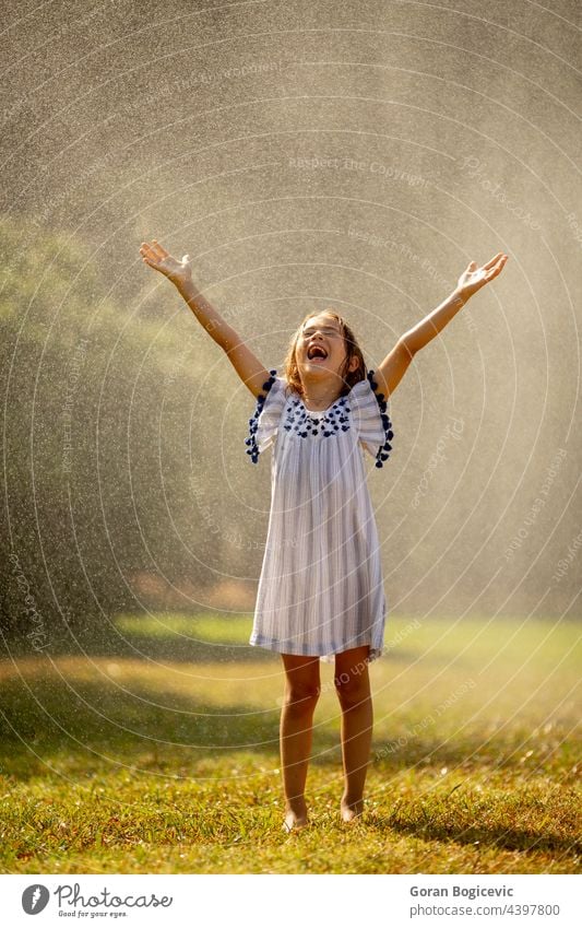 Niedliches kleines Mädchen hat Spaß unter Bewässerung Sprinkler Glück Kind Sommer Fröhlichkeit Freude Sprinkleranlage Spray nass aktiv Wasser im Freien